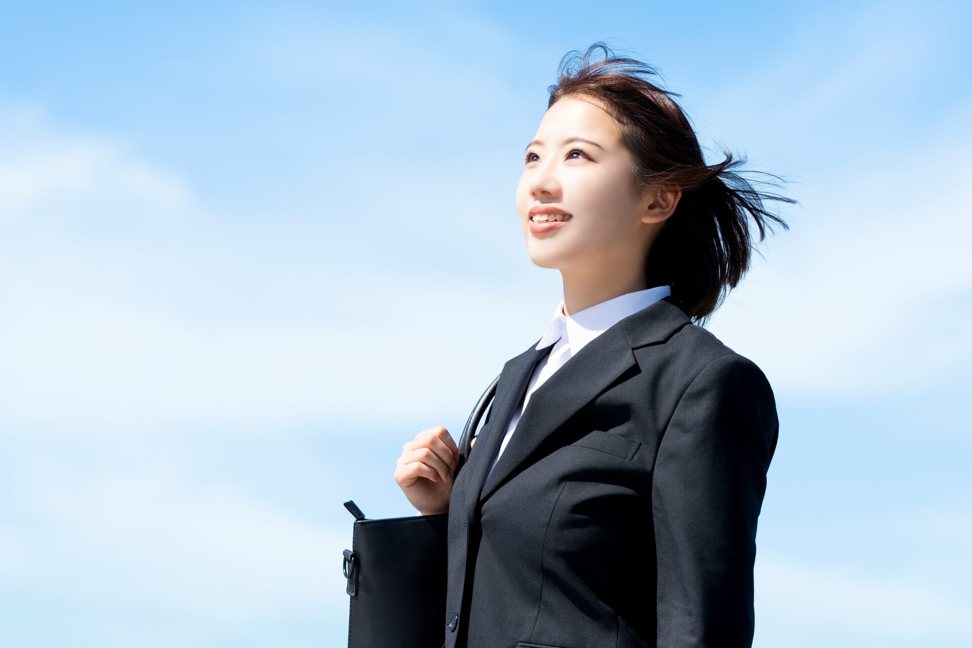 青空の下で自信溢れる若いビジネス女性